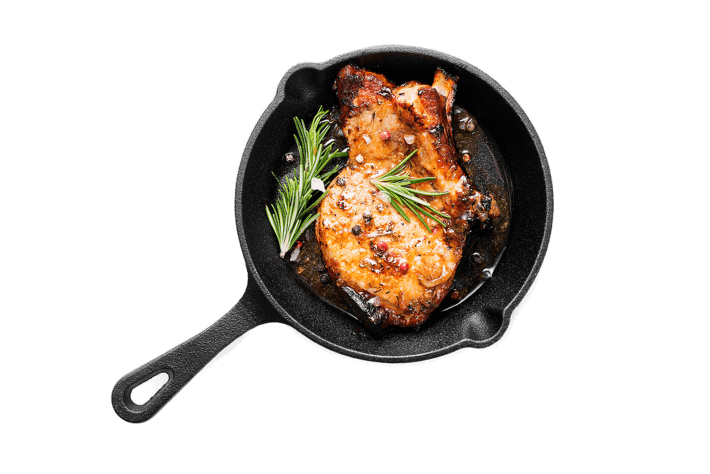 Fried pork steak in frying pan isolated on white background.